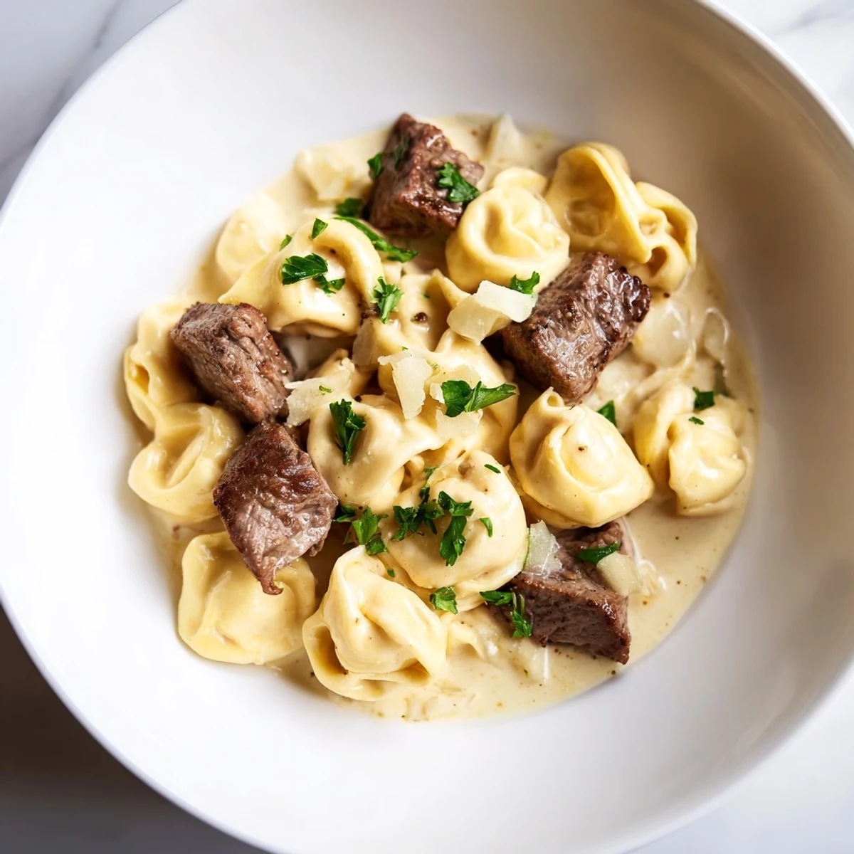 Creamy garlic steak tortellini garnished with fresh parsley and grated parmesan cheese